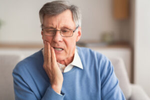 older man with glasses having pain in his neck and jaw